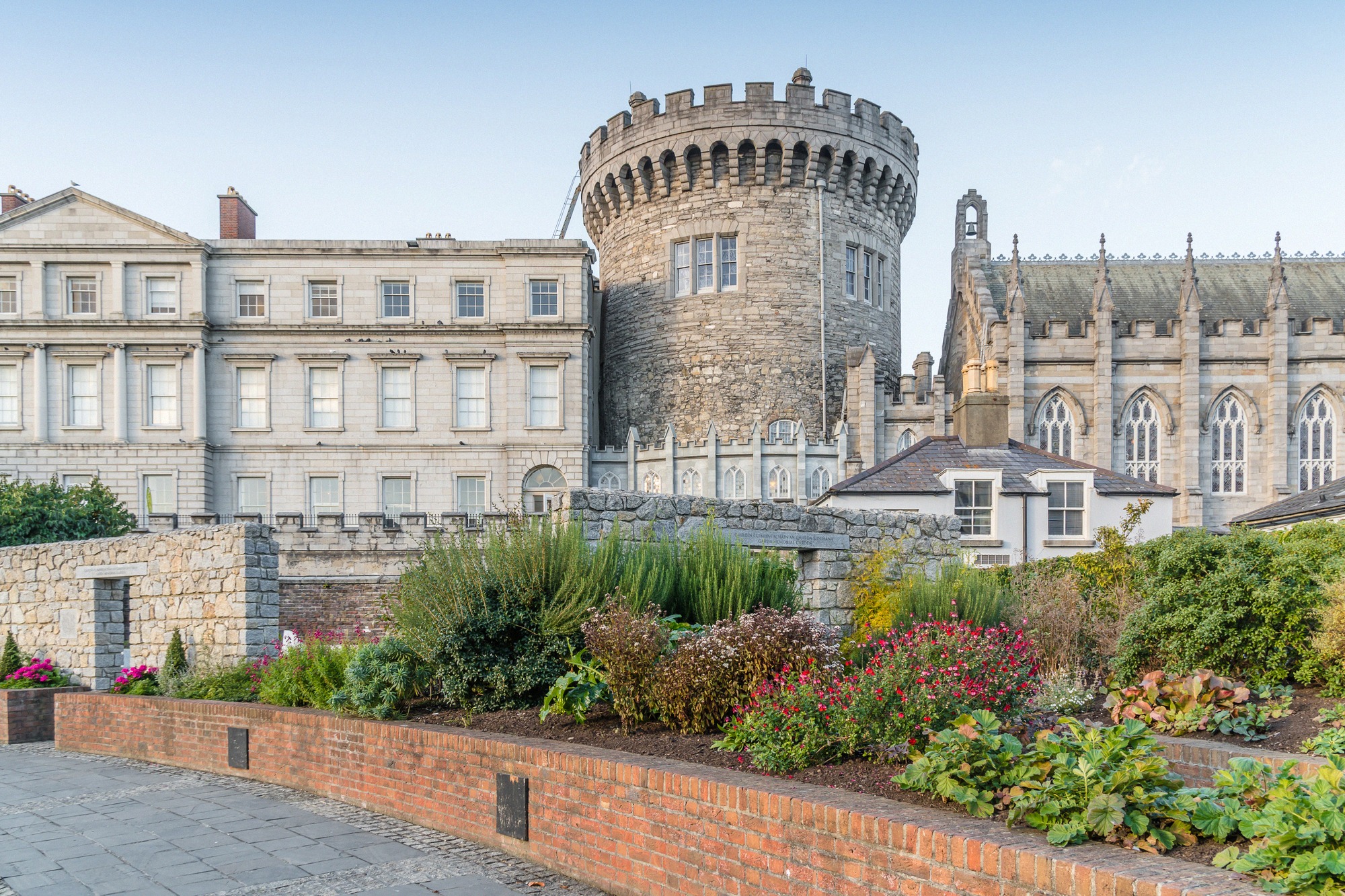 Eingangstor des Dublin Castle mit charakteristischen Zinnen und grünem Rasen im Vordergrund.